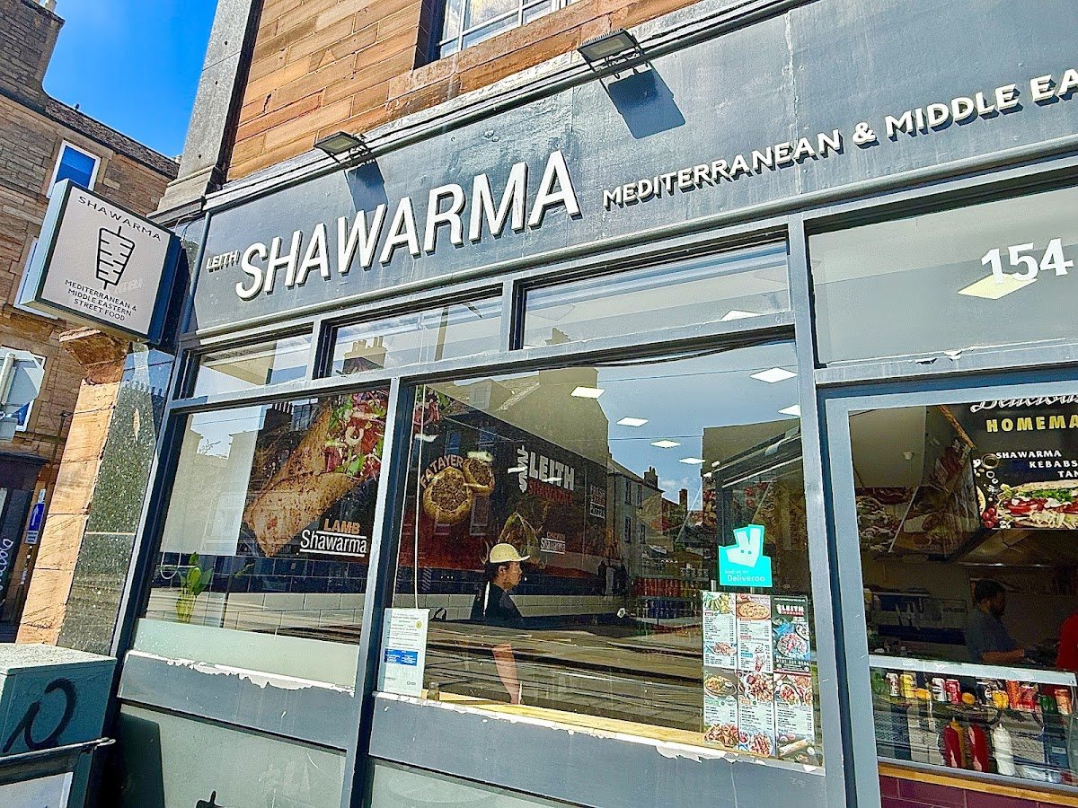 The Leith Shawarma shopfront: a grey fascia reading LEITH SHAWARMA, Mediterranean & Middle Eastern, with the number 154, big windows with menu posters, and a hanging sign.